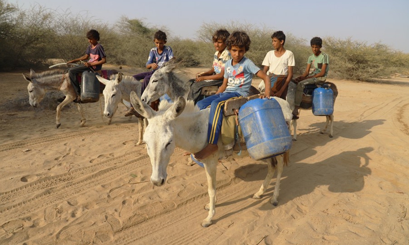 Yemeni children ride on donkeys with their water tanks after they filled them up at a charitable water station in Abs District, Hajjah Province, northern Yemen on March 21, 2022.(Photo: Xinhua)