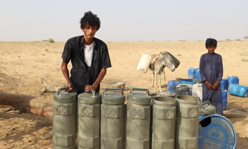 A Yemeni man stands near his water tanks made from discarded ammunition containers after he filled them up at a charitable water station in Abs District, Hajjah Province, northern Yemen on March 21, 2022.(Photo: Xinhua)