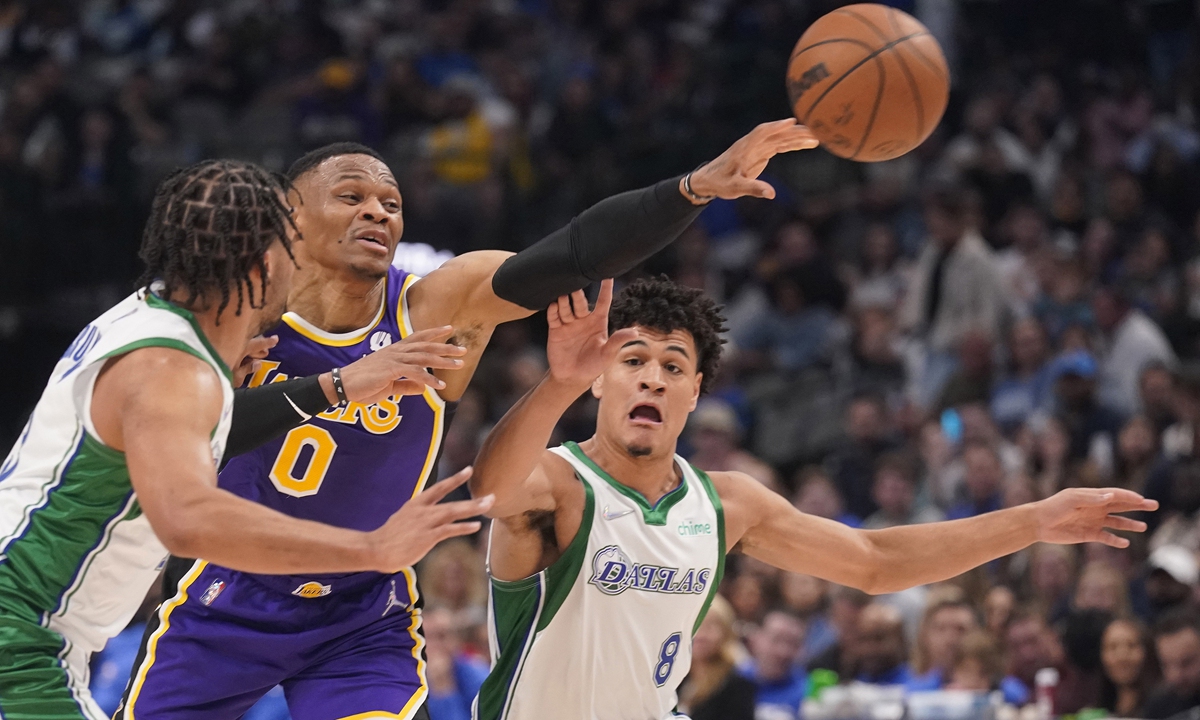 Los Angeles Lakers guard Russell Westbrook (center) passes off between Dallas Mavericks defenders Josh Green (right) and Jalen Brunson on March 29, 2022 in Dallas, Texas. Photo: VCG