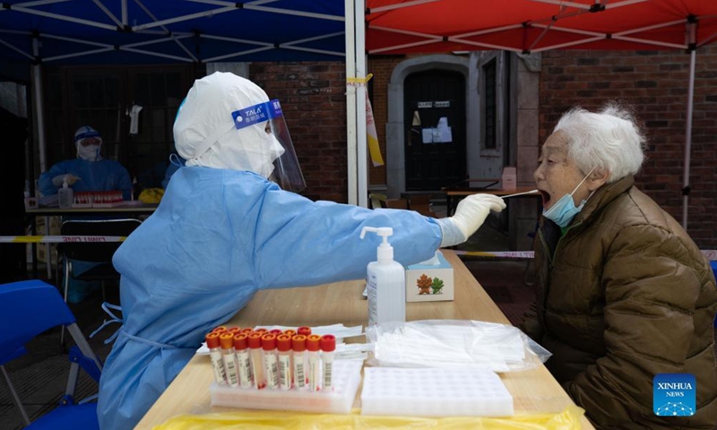 A medical worker takes a swab sample from a woman for nucleic acid test in Changning District of east China's Shanghai, April 1, 2022. Shanghai has launched a nucleic acid testing campaign in areas west of the Huangpu River from Friday amid the second phase of the city's closed-off management.Photo:Xinhua
