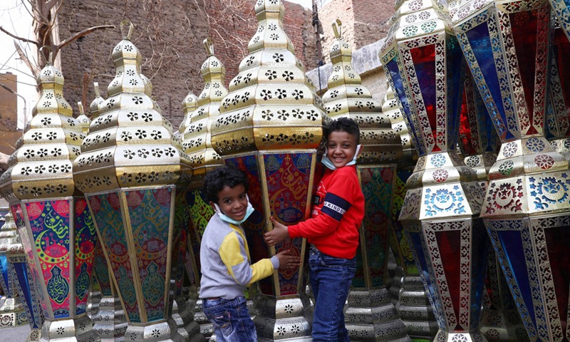 Children pose for photos with a lantern ahead of the holy month of Ramadan at a lantern market in Cairo, Egypt, on March 18, 2022. (Photo: Xinhua)