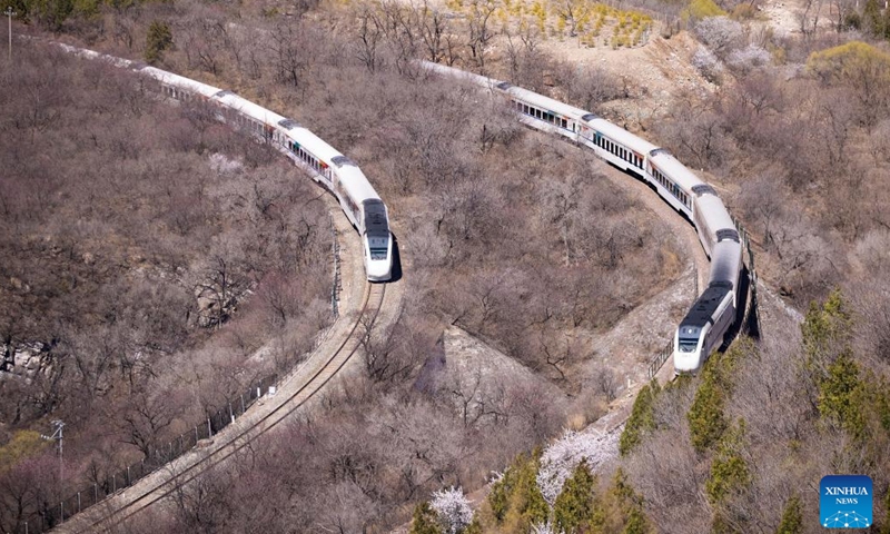 Suburban trains run amid blooming flowers near the Juyongguan section of the Great Wall in Beijing, capital of China, April 2, 2022.Photo:Xinhua