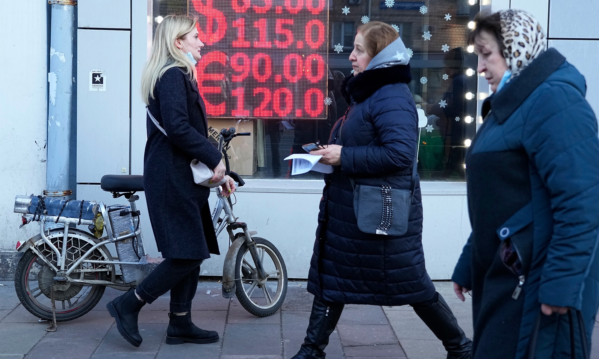 People walk past a currency exchange office screen displaying the exchange rates of US Dollar and Euro to Russian Rubles in Moscow, on Febuary 28, 2022. Photo: VCG