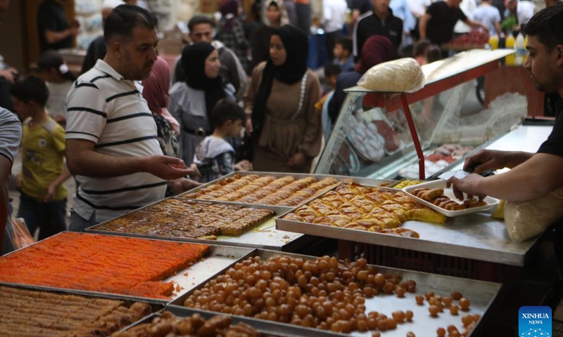 A man buys sweets at a market during the Islamic holy month of Ramadan in the West Bank city of Hebron, on April 5, 2022. (Photo by Mamoun Wazwaz/Xinhua)