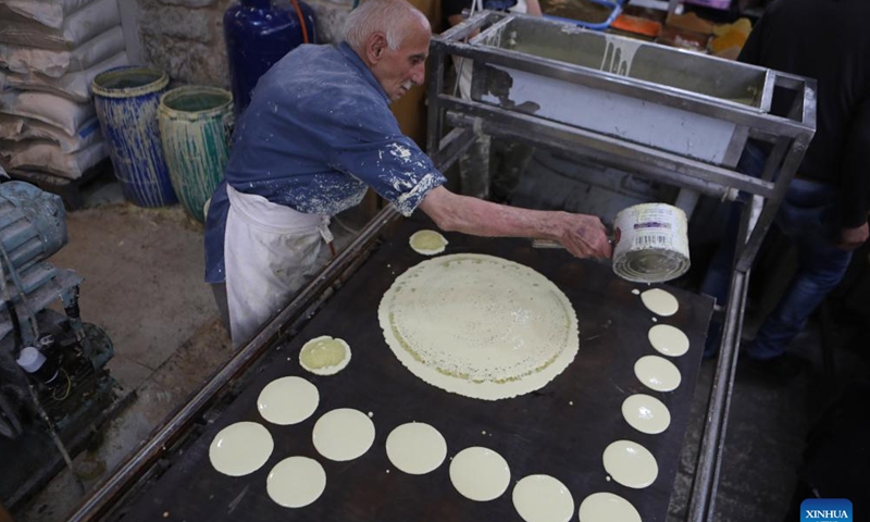 A man makes traditional sweets known as Qatayef at a market during the Islamic holy month of Ramadan in the West Bank city of Hebron, on April 5, 2022. (Photo by Mamoun Wazwaz/Xinhua)