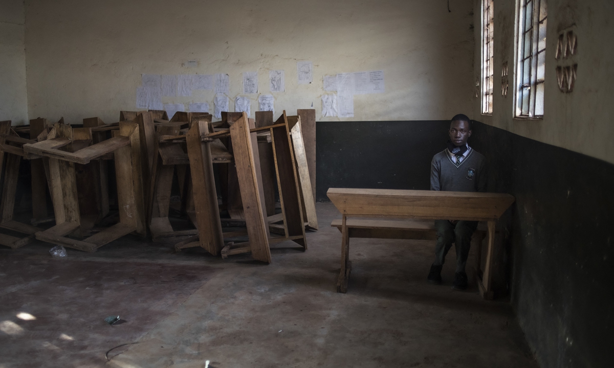 A student sits alone in a classroom after reporting back to school on day one of reopening following an almost two-year closure of learning institutions as part of government measures to curb COVID-19 in Kampala, Uganda on January 10, 2022. Photo: AFP