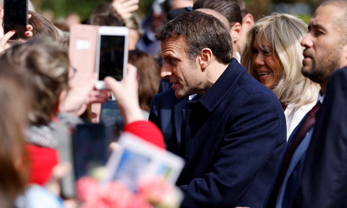 France's President Emmanuel Macron (center) and his wife Brigitte Macron (2nd from right) speak with onlookers ahead of casting their ballots for the first round of France's presidential election at a polling station in Le Touquet, northern France on April 10, 2022.