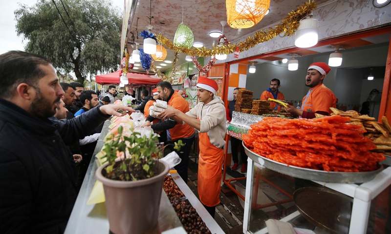 Photo taken on April 6, 2022 shows people buying traditional desserts during the holy month of Ramadan in Boufarik, Algeria.(Photo: Xinhua)