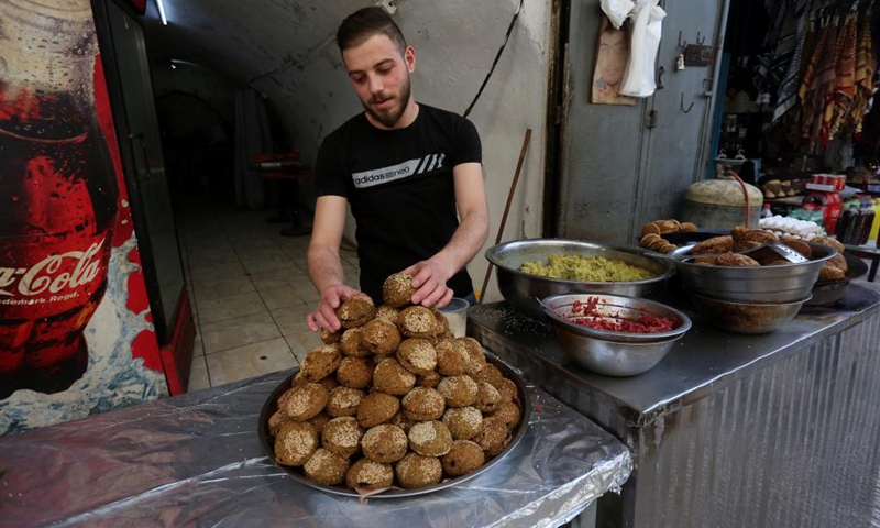 A Palestinian man sells falafel at a market during the Islamic holy month of Ramadan in the West Bank city of Nablus, on April 6, 2022.(Photo: Xinhua)