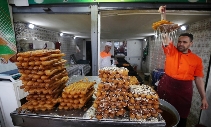 Photo taken on April 6, 2022 shows vendors making traditional desserts known as Zalabia during the holy month of Ramadan in Boufarik, Algeria.(Photo: Xinhua)