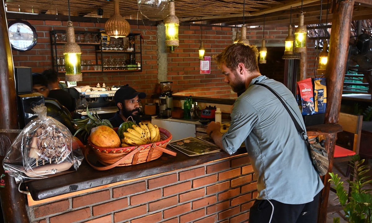A cafe manager speaks with a tourist in Mirissa, Sri Lanka, on March 26, 2022. Photo: AFP