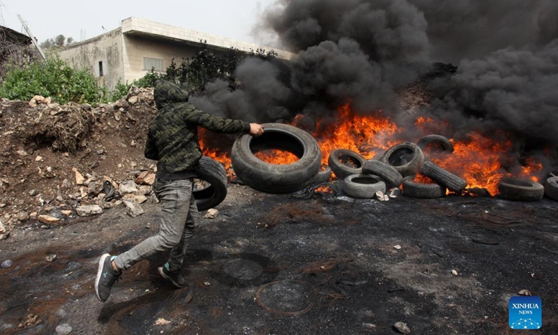 A Palestinian protester burns tires during clashes with Israeli soldiers after a protest against the expanding of Jewish settlements in Kufr Qadoom village near the West Bank city of Nablus, on April 8, 2022.(Photo: Xinhua)