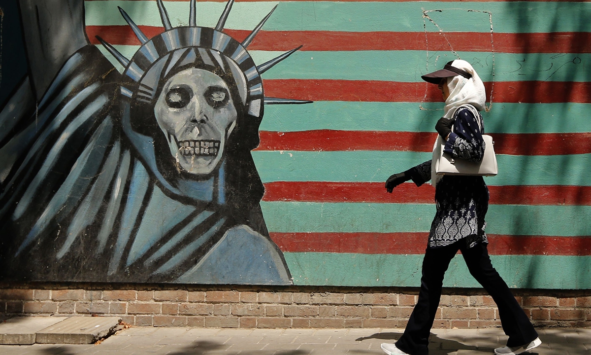 A woman walks past the landmark graffiti on the walls of the former US embassy in Tehran, Iran.  Photo: AFP