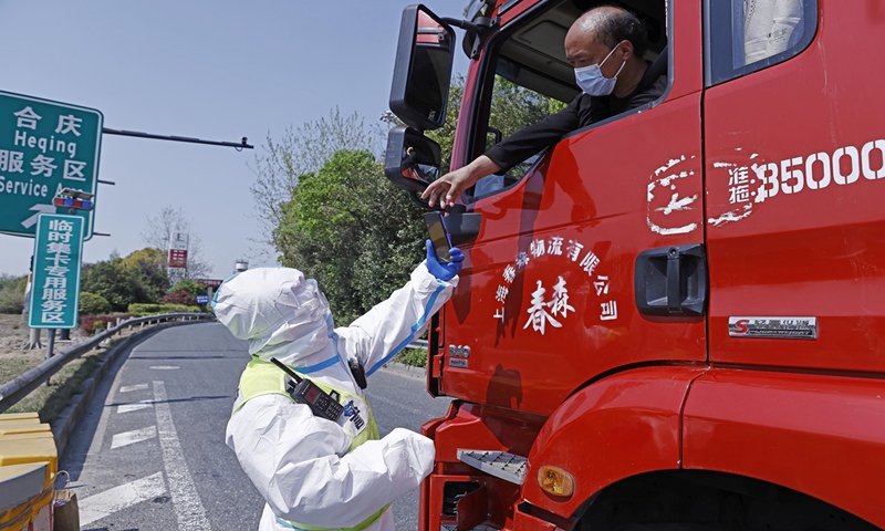 A policeman checks the nucleic acid test result of a truck driver at Heqing expressway service station in Shanghai, on April 11, 2022. Photo: VCG