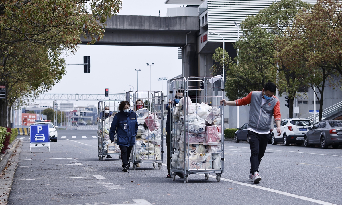 Grocery store deliverymen carry the residential group purchase items to their designated areas in Shanghai on April 1, 2022. Photo: VCG