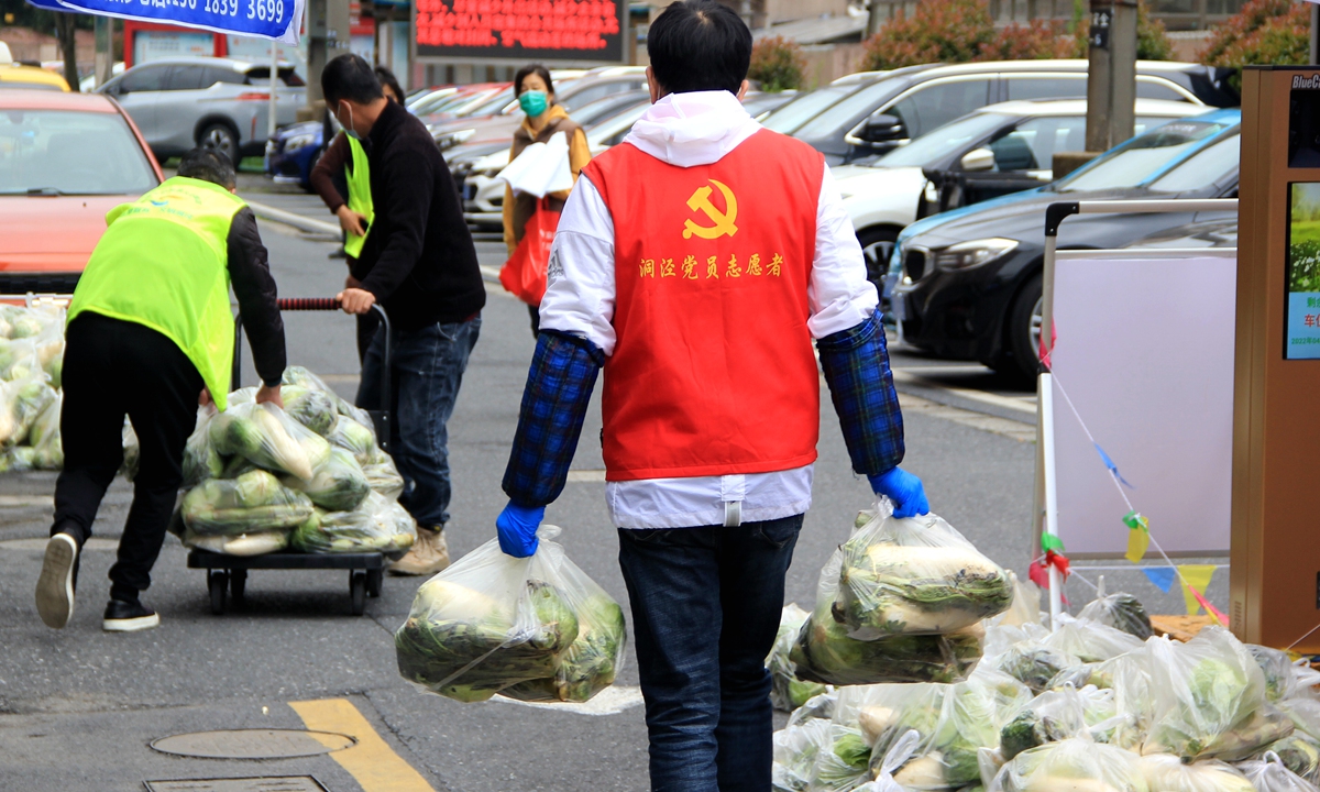 Volunteers carry supplies at  community gates in Songjiang district, Shanghai on April 15, 2022. Photo: IC