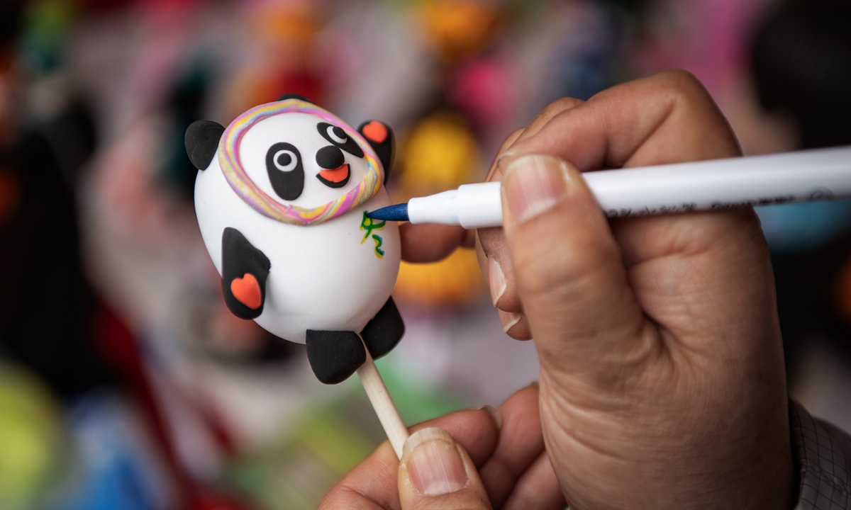 From left: An artist works on a sugar Bing Dwen Dwen figurine. Two children enjoy their sugar Bing Dwen Dwen figurines. Photos: IC