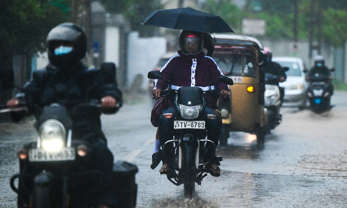 commuters ride along a road during a heavy rainfall in colombo