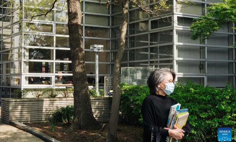 A visitor carrying books walks in a park of the Suginami City Central Library in Tokyo, Japan, April 10, 2022.(Photo: Xinhua)