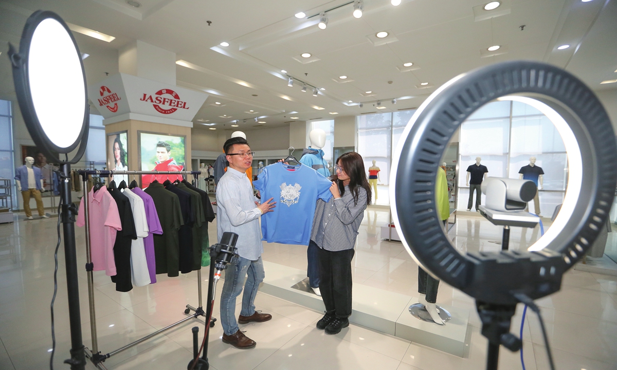 Two employees from East China's Shandong Province sell clothing products exported to overseas markets via the Canton fair online
platform on April 15, 2022. Photo: Xinhua