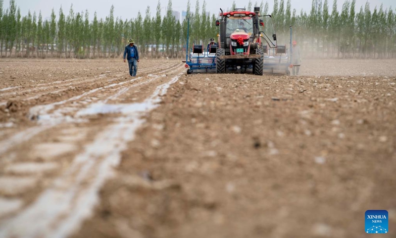 Ili Mehmet looks on as workers operate a seeder in his cotton field in Shawan, northwest China's Xinjiang Uygur Autonomous Region, April 19, 2022. Ili Mehmet, 50, lives in Shawan, a major cotton-producing area in Xinjiang.Photo:Xinhua