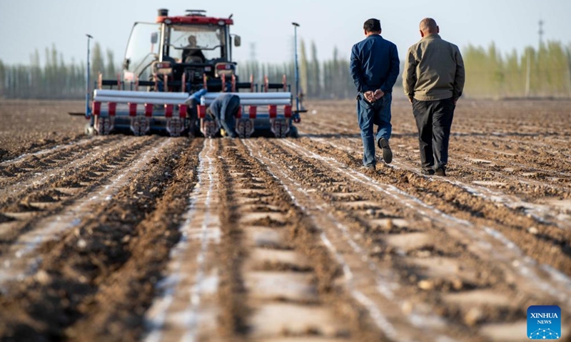 Ili Mehmet (2nd, R) discusses sowing plans with Duan Zhizhong as workers operate a seeder in his cotton field in Shawan, northwest China's Xinjiang Uygur Autonomous Region, April 16, 2022. Ili Mehmet, 50, lives in Shawan, a major cotton-producing area in Xinjiang.Photo:Xinhua