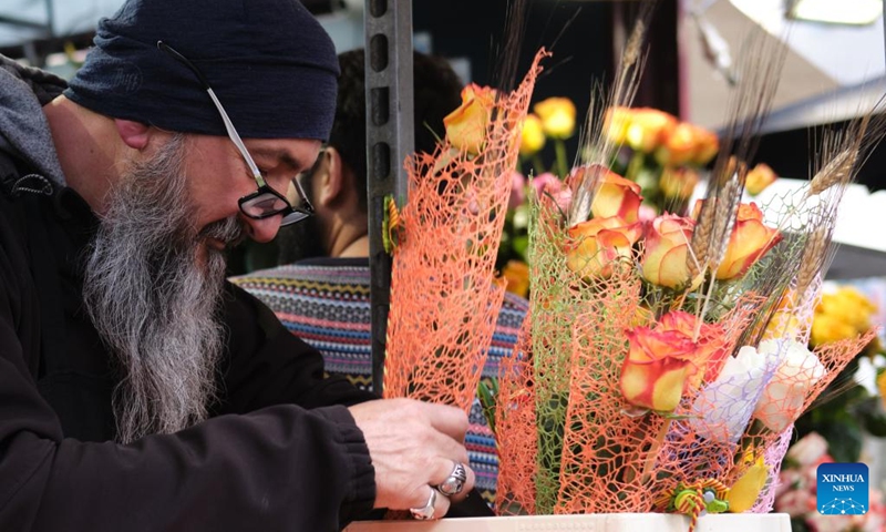 A man selects roses in Barcelona, Spain, April 23, 2022. St. George's Day usually sees the streets of Barcelona filled with parades of people exchanging books and flowers with their loved ones. (Xinhua/Meng Dingbo)