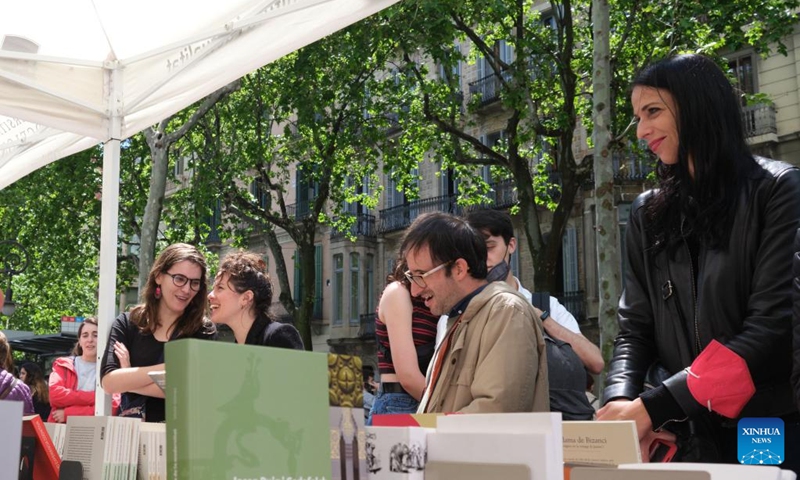 People select books at a stall in Barcelona, Spain, April 23, 2022. St. George's Day usually sees the streets of Barcelona filled with parades of people exchanging books and flowers with their loved ones. (Xinhua/Meng Dingbo)