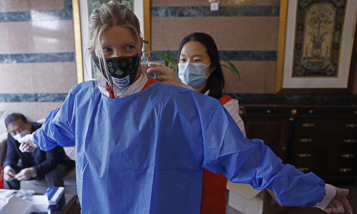 Chinese volunteers in Huashan Huayuan community help Erika, a volunteer from the US, put on her personal protective suit in Shanghai, on April 6. Photo: IC