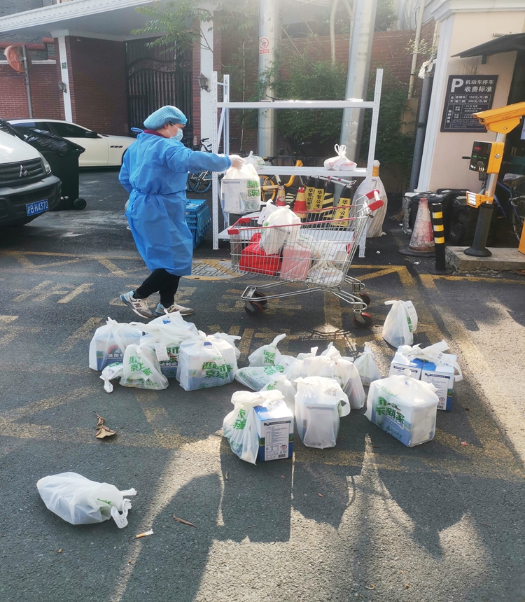 A community volunteer supports the delivery of goods for residents at the gate of the community. Photo: IC