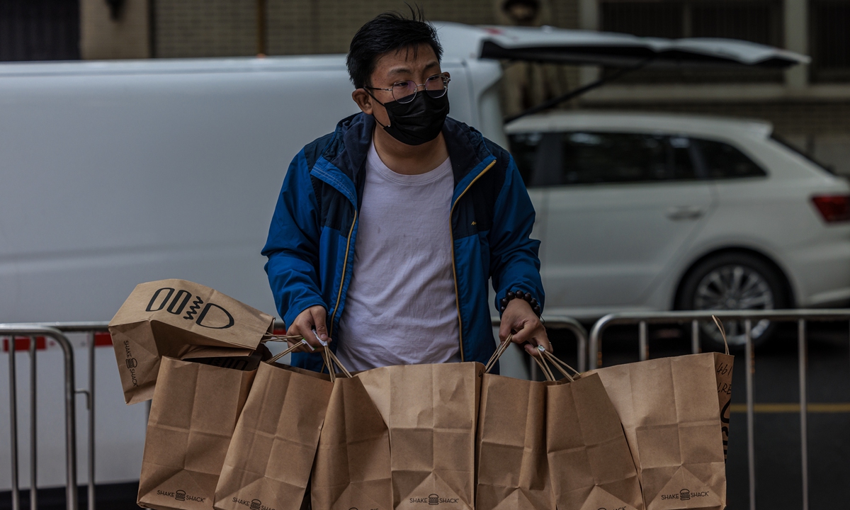 A delivery worker brings a large batch of Shake Shack burgers to a residential community under lockdown in Shanghai, China, on April 23.Photo:IC