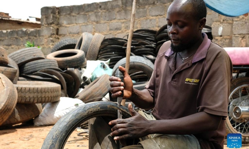 Eric Rugomoka cuts a worn-out tire at a tire workshop in Makerere Kivulu of Kampala, Uganda, March 7, 2022.(Photo: Xinhua)