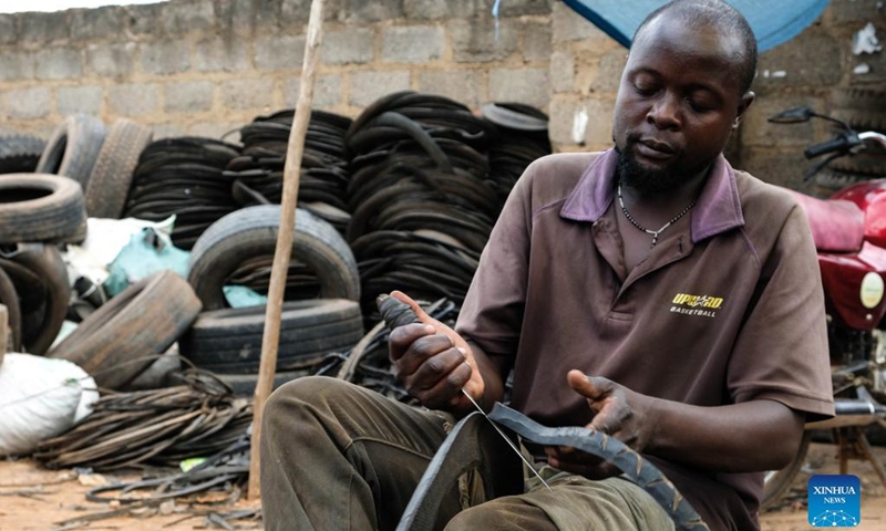 Eric Rugomoka cuts a worn-out tire at a tire workshop in Makerere Kivulu of Kampala, Uganda, March 7, 2022.(Photo: Xinhua)