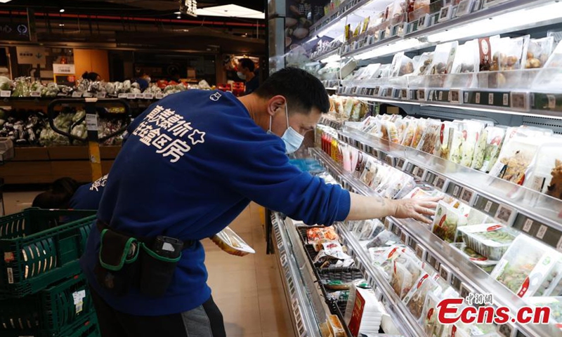A staff member checks products on a shelf at a Hema Fresh store in Chaoyang District, Beijing, April 26, 2022. (Photo: China News Service/Fu Tian)