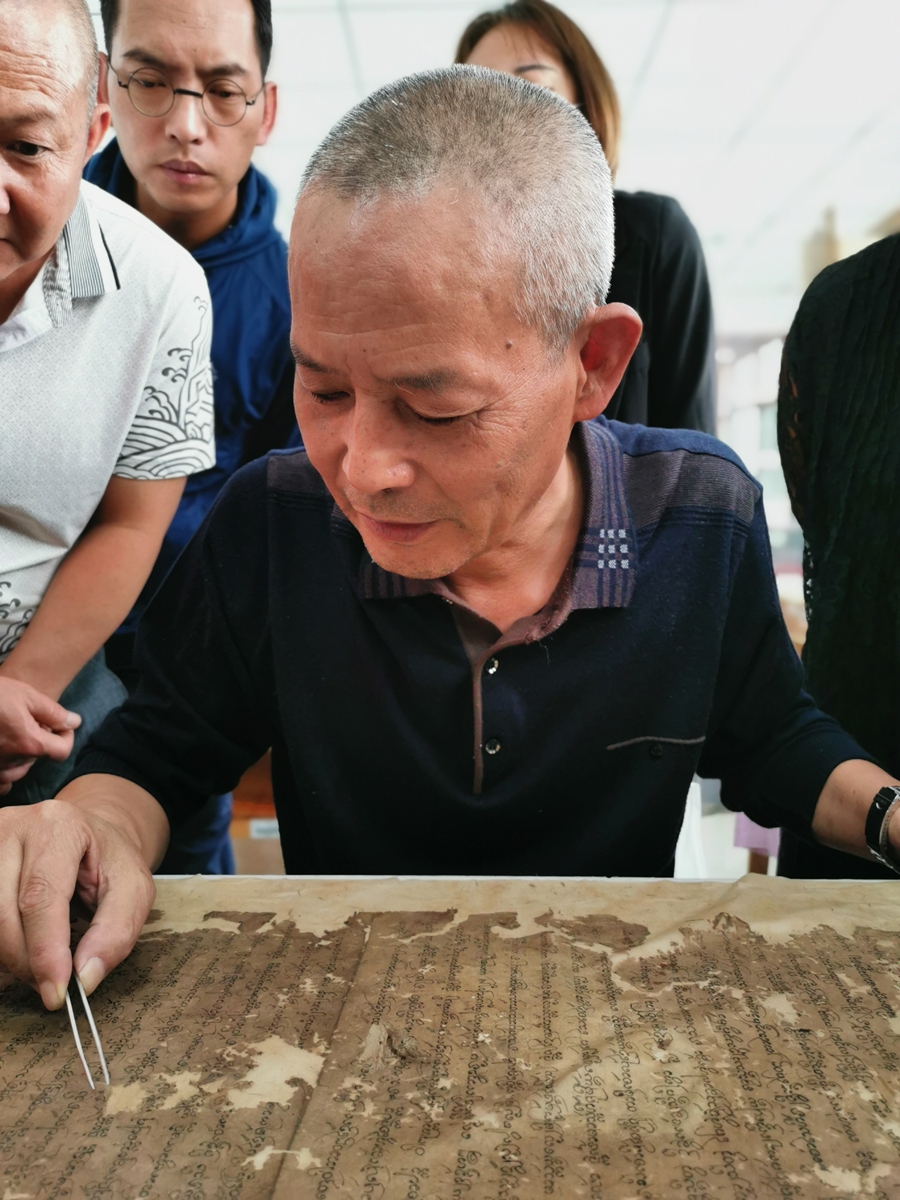 Yang Liqun(front) restores an ancient manuscript as his apprentices observe. Photo: Courtesy of Yunnan Provincial Library