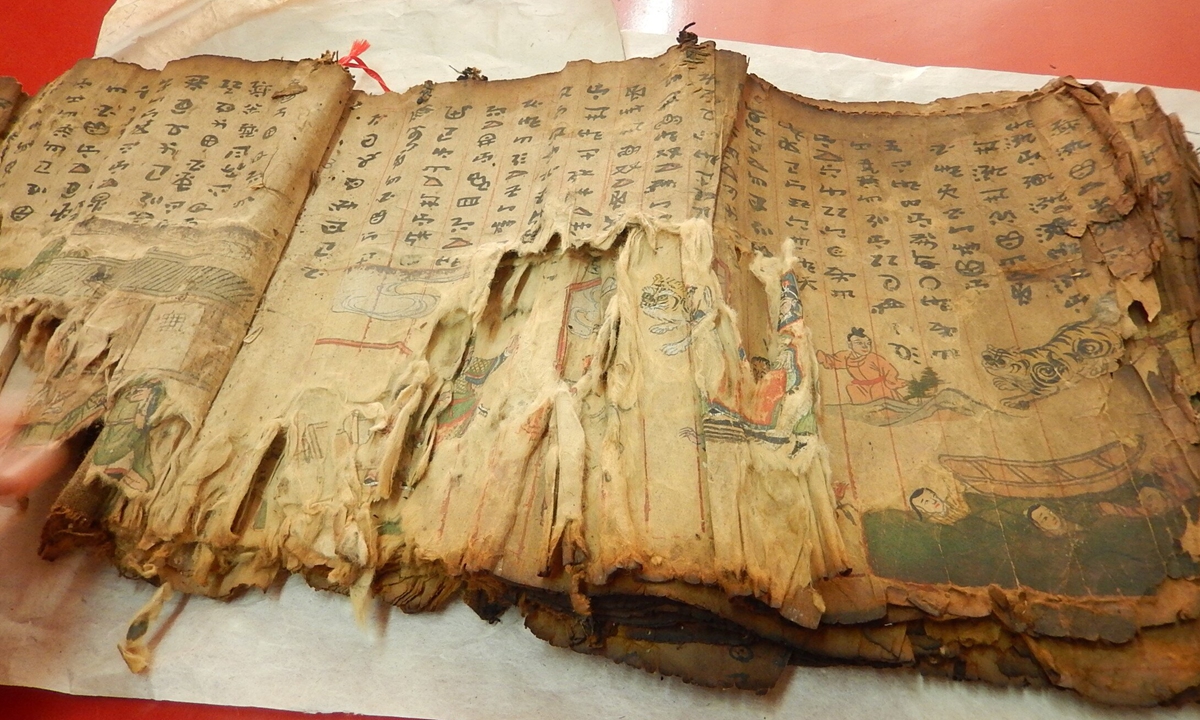 Yang Liqun(front) restores an ancient manuscript as his apprentices observe. Photo: Courtesy of Yunnan Provincial Library