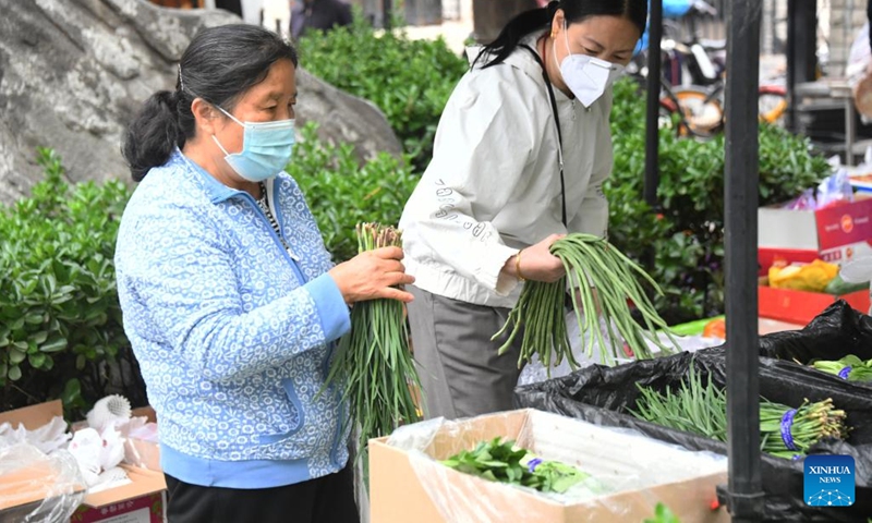 Residents select vegetables at a residential area in Haidian District, Beijing, capital of China, April 27, 2022. Communities in Haidian District have strengthened the supply of daily necessities for residents following a recent COVID-19 resurgence. (Xinhua/Ren Chao)