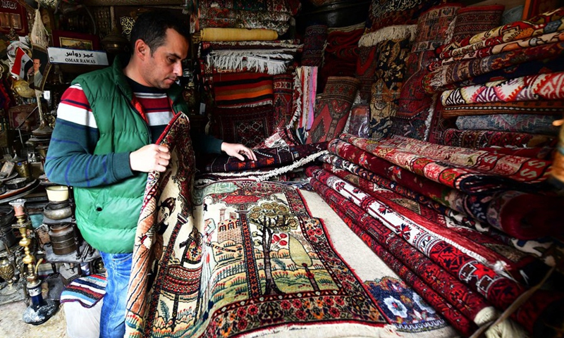 Omar Rawas, a carpet weaver, is seen fixing carpets at his workshop in Syria's northern city of Aleppo on March 8, 2022.(Photo: Xinhua)