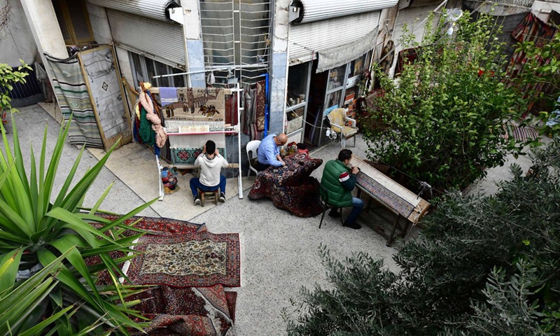 Omar Rawas, a carpet weaver, is seen fixing carpets at his workshop in Syria's northern city of Aleppo on March 8, 2022. (Photo: Xinhua)