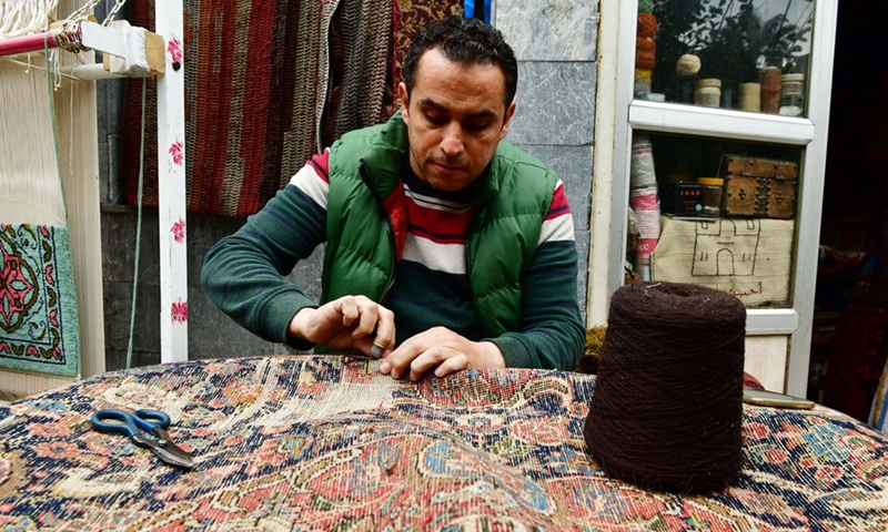 Omar Rawas, a carpet weaver, is seen fixing carpets at his workshop in Syria's northern city of Aleppo on March 8, 2022.(Photo: Xinhua)