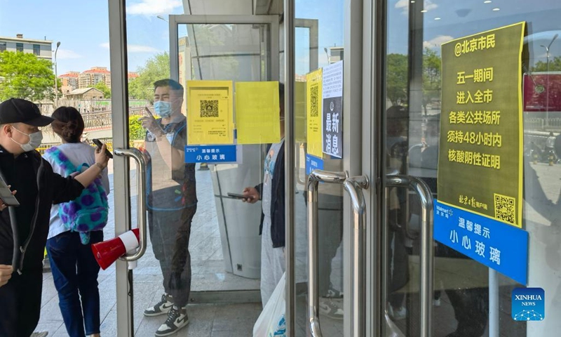 A staff member checks the nucleic acid test results of customers outside a Walmart store in Beijing, capital of China, May 1, 2022. A negative nucleic acid test result within 48 hours is required to enter public venues during the Labor Day holiday in Beijing. Photo: Xinhua