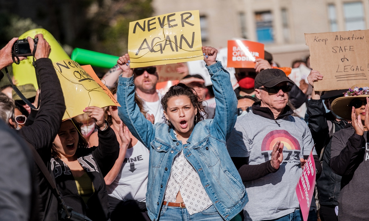 A demonstrator holds up a coat hanger, a symbol of the reproductive rights movement, and a sign reads Never Again as pro-choice protesters gather in large numbers in front of the federal building to defend abortion rights in San Francisco on May 3, 2022. Photo: AFP
