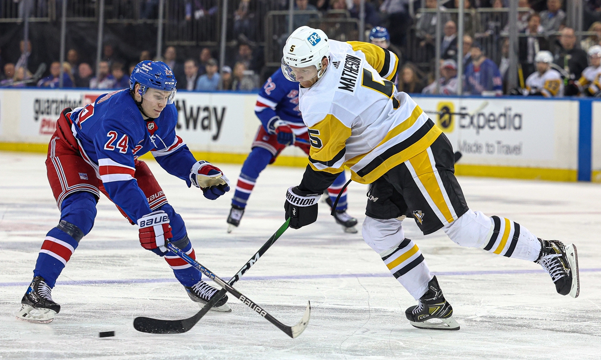 Pittsburgh Penguins' Mike Matheson (right) plays the puck against New York Rangers' Kaapo Kakko on May 3, 2022 in New York City. Photo: IC