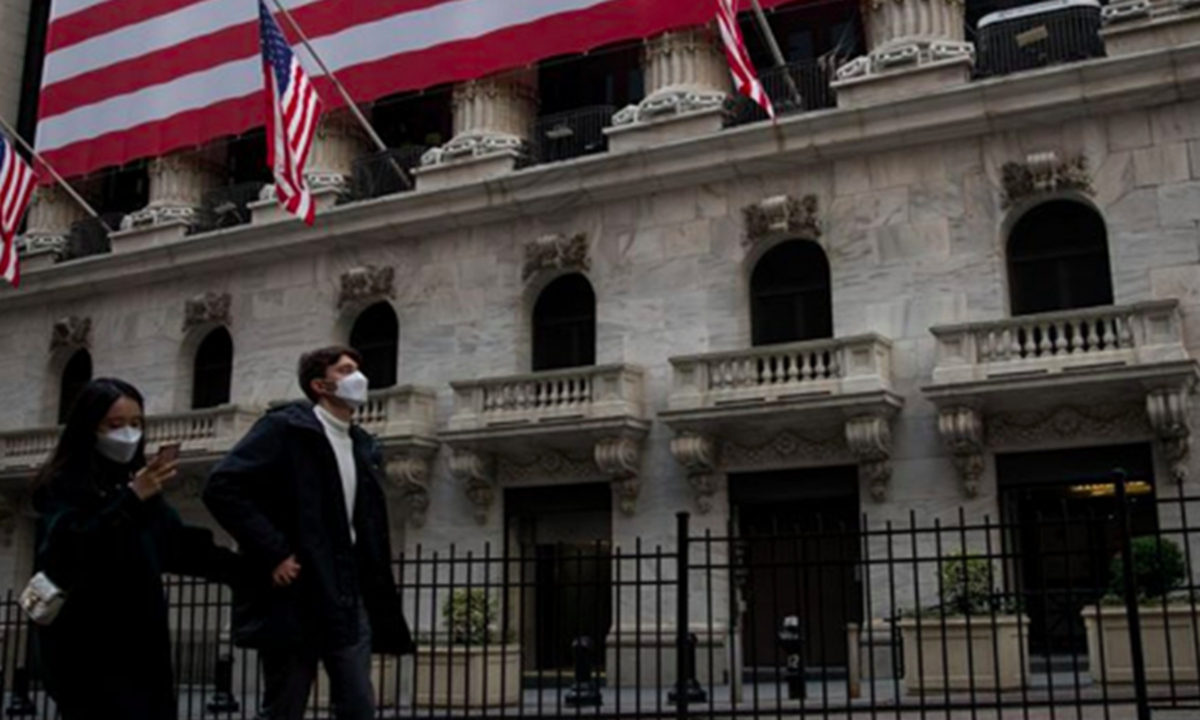 Pedestrians wearing face masks walk past the New York Stock Exchange in New York, the US. Photo: Xinhua