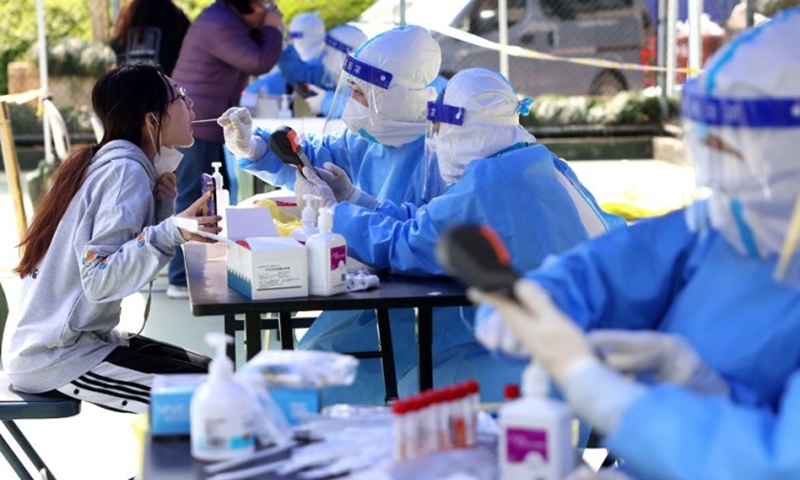 Medical workers take a swab sample from a resident for nucleic acid test at a community in Putuo District of Shanghai, east China, April 6, 2022. (Xinhua）