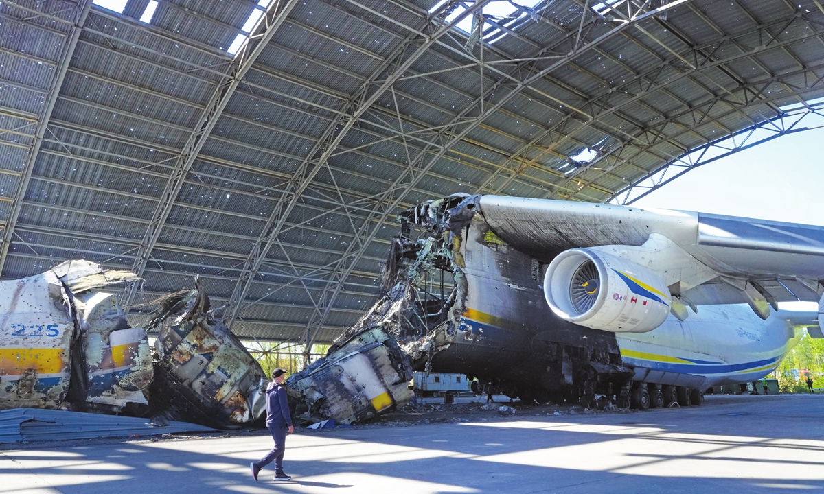 A man passes by Antonov An-225, the world's biggest cargo aircraft, and military vehicles destroyed during recent fighting between Russian and Ukrainian forces, at the Antonov airport on the outskirts of Kiev, Ukraine, on May 5, 2022. Photo: VCG
