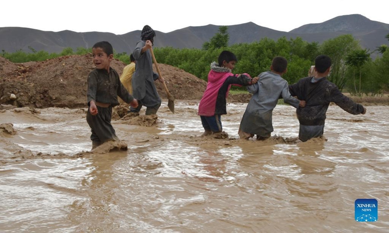 Children walk through flood water after a heavy rain in Baghlan province, Afghanistan, May 4, 2022. Eight people have been confirmed dead and 13 others injured as floods swept parts of the northern Baghlan and western Badghis provinces on Wednesday, officials said Thursday.(Photo: Xinhua)