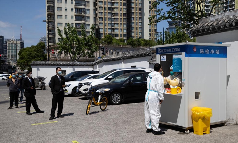 A staff member takes a swab sample from a woman for nucleic acid test in Huangpu District, east China's Shanghai, May 8, 2022. Shanghai has set up fixed and mobile acid testing sites in areas such as residential communities, office spaces, business parks and in the vicinities of subway and other public transport stations in accordance with the epidemic situation.Photo:Xinhua