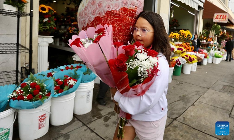 A girl carrying flowers is seen at a flower market on Mother's Day in downtown Los Angeles, the United States, on May 8, 2022.Photo:Xinhua