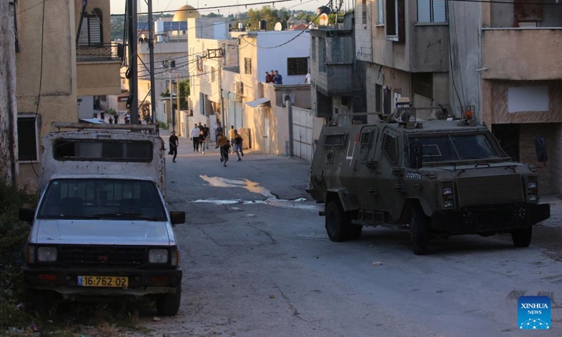 Palestinian protesters hurl stones at an Israeli security forces' vehicle during a raid on the houses of the two Palestinian suspects in the village of Romana near the West Bank city of Jenin, on May 8, 2022.Photo:Xinhua